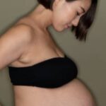 This is an image of a pregnant woman looking at the size of her belly