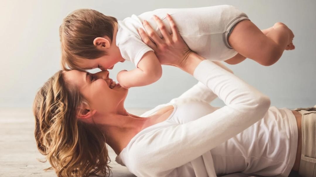 this is an image of a mother holding up her baby and smiling